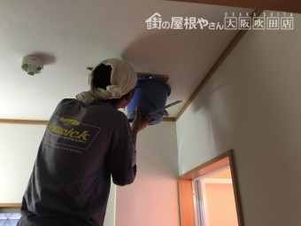天井から流れ落ちる雨水をバケツでキャッチする職人