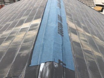 台風で被災したスレート屋根の大棟板金に防水シートで応急処置