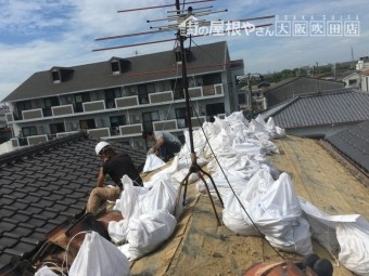屋根の土を土嚢に入れる
