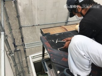 屋根の古い板金を撤去する職人