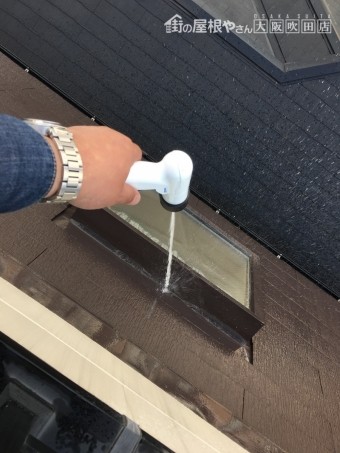 勾配屋根にある採光用の出窓に散水して雨水侵入の経路を調べる
