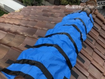 台風の被害を受けた屋根瓦にブルーシートで応急処置