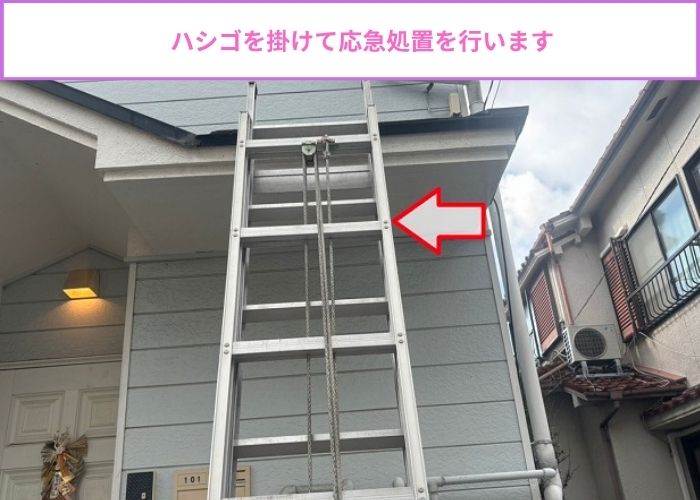 アパートにハシゴを掛けて雨樋の応急処置を実施