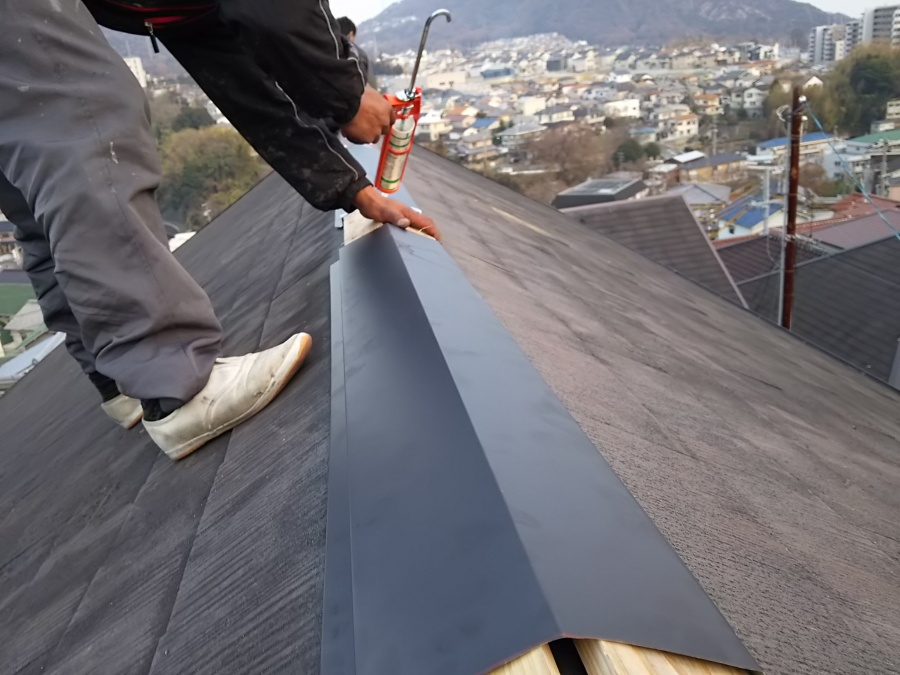 新しいシルバーブラックの棟板金を施工しています。