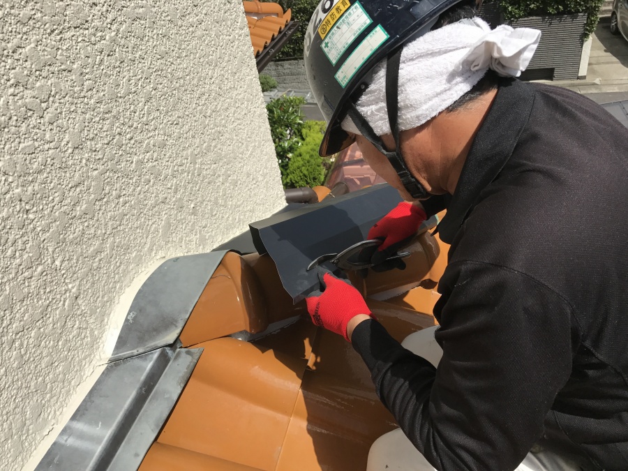 屋根補修用に成形した板金を取り合いに取り付ける職人