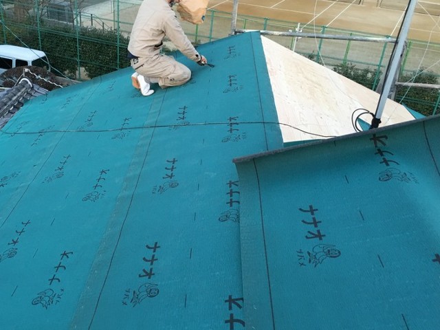 屋根に防水シートを施工中