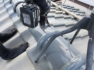 丸瓦をパッキン付きビスで留めている様子