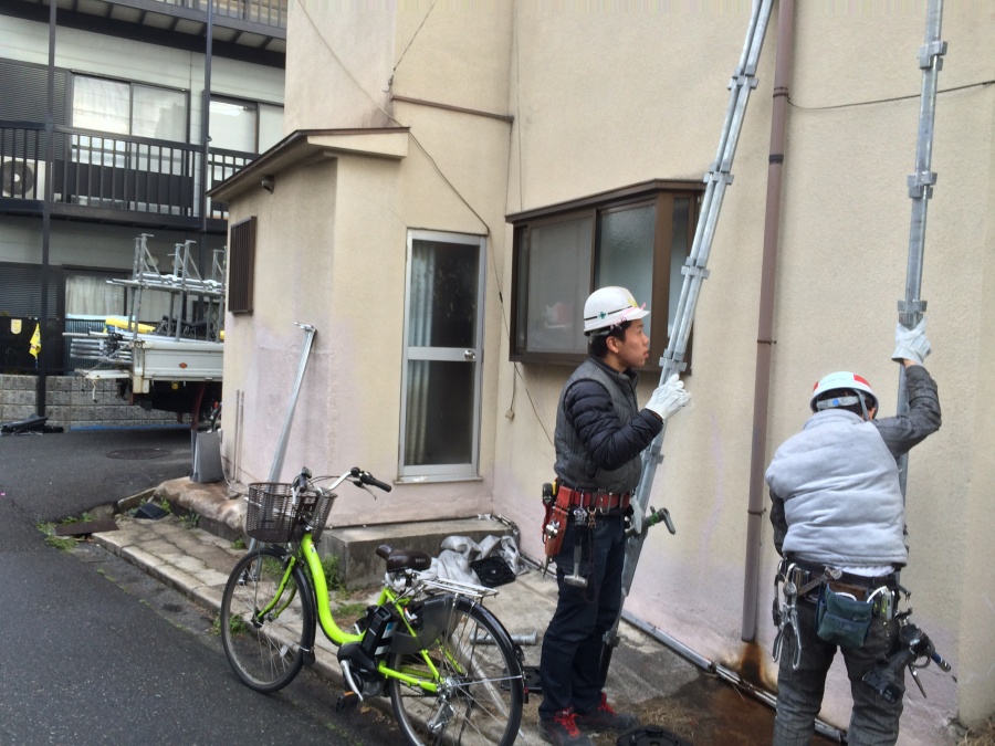 長屋造りの瓦屋根補修工事現場にて外壁をチェックする職人