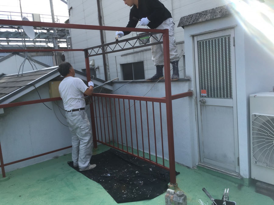 屋上鉄柵に錆止め塗装をする職人