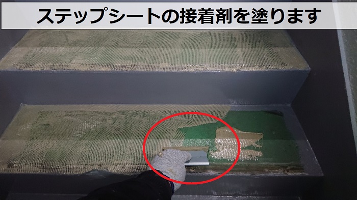 豊中市ハイツの共用階段にステップシートを貼るための接着剤を塗っている様子