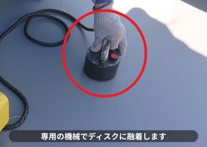 豊中市で屋上の雨漏り修理として塩ビシート防水機械固定工法でディスクに融着している様子