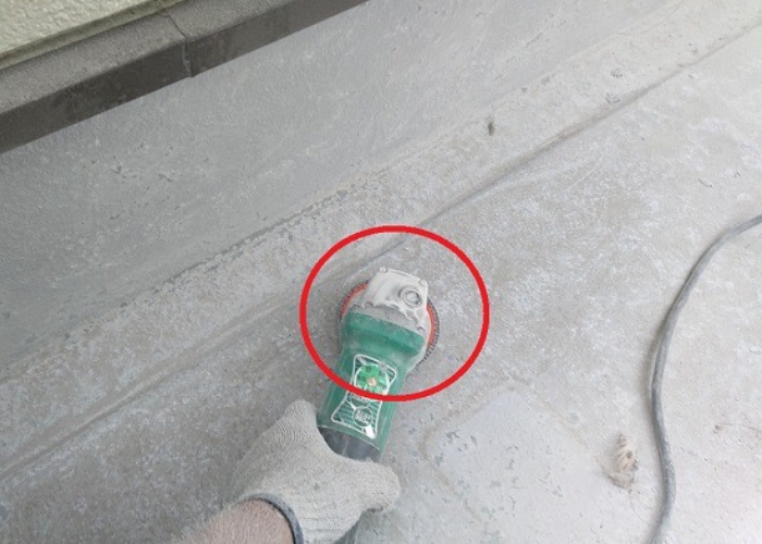 剥がれたベランダ防水をケレンしている様子