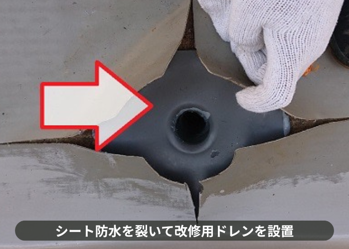 枚方市雨漏りしているシート防水を裂いて改修用ドレンを設置している様子