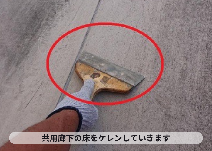 アパートの共用廊下の床をケレンしている様子